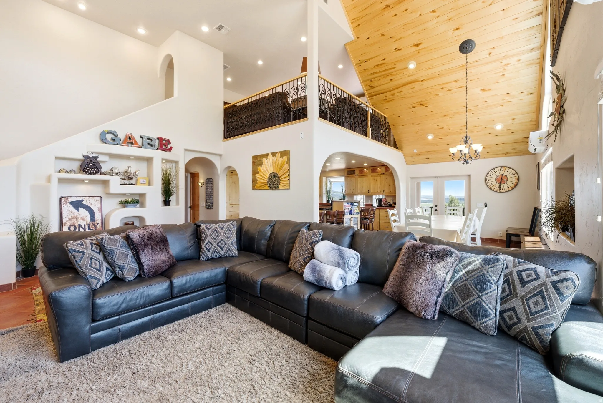 Vaulted wood-paneled ceiling with recessed lighting and chandelier