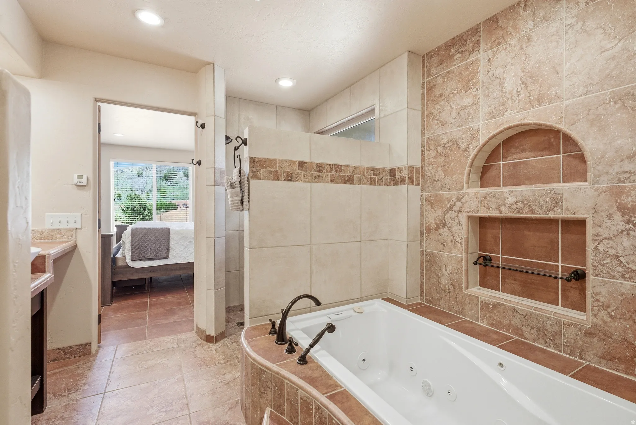 Tiled bathroom featuring a built-in jetted tub, a tiled shower enclosure, recessed lighting, and an arched wall niche