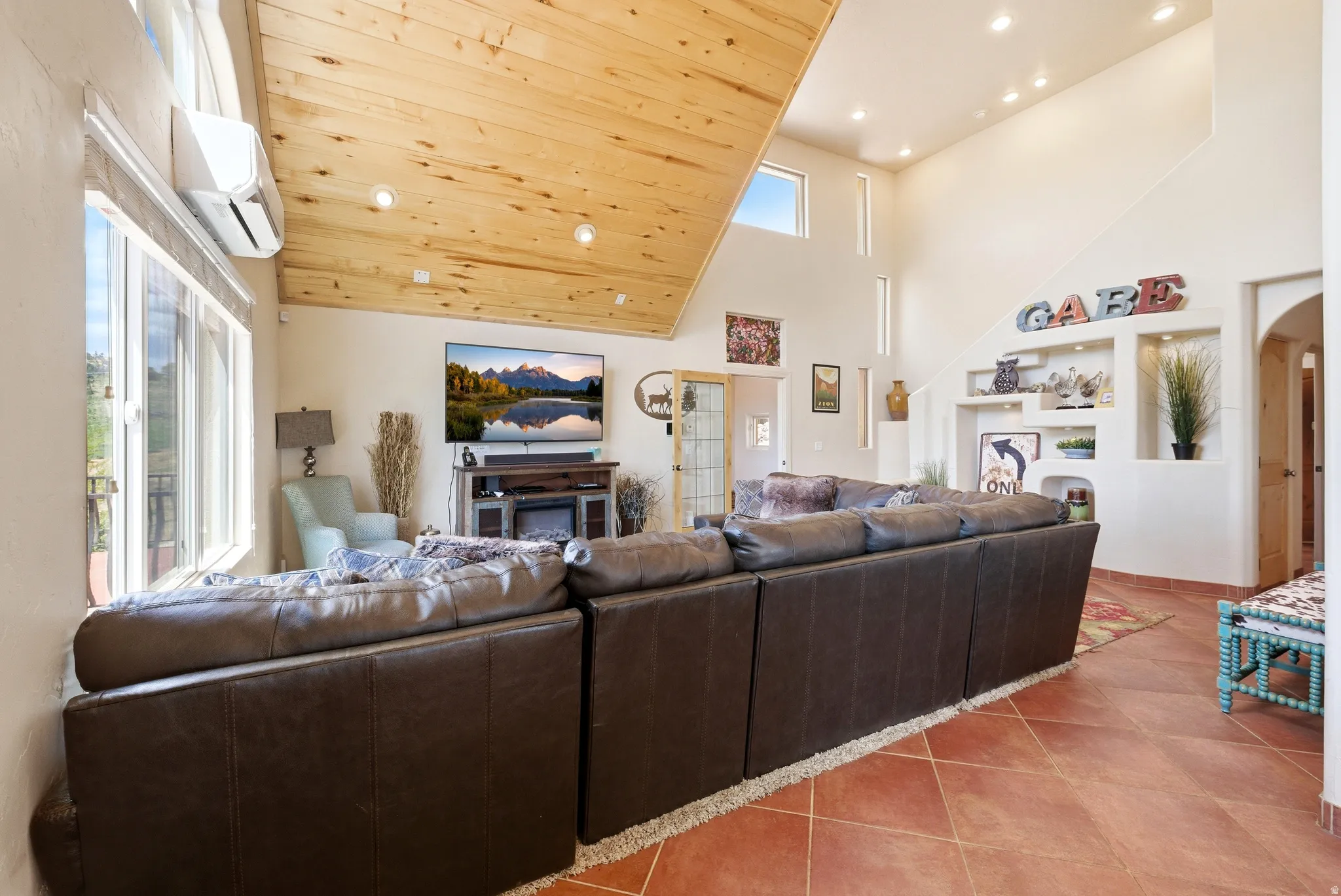 Spacious living area featuring a vaulted wood-finish ceiling, multiple windows, and integrated wall niches