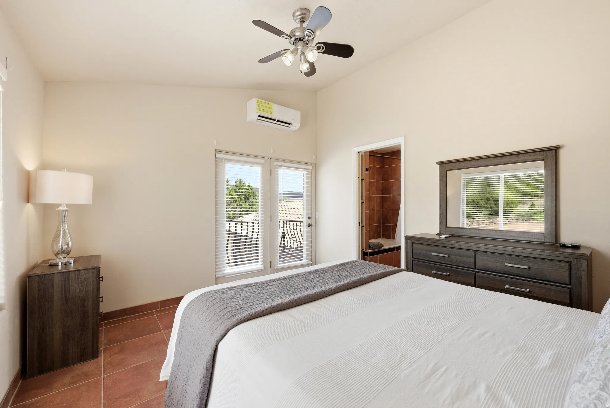 Bedroom featuring terracotta tile flooring, a vaulted ceiling, and an overhead ceiling fan with lighting