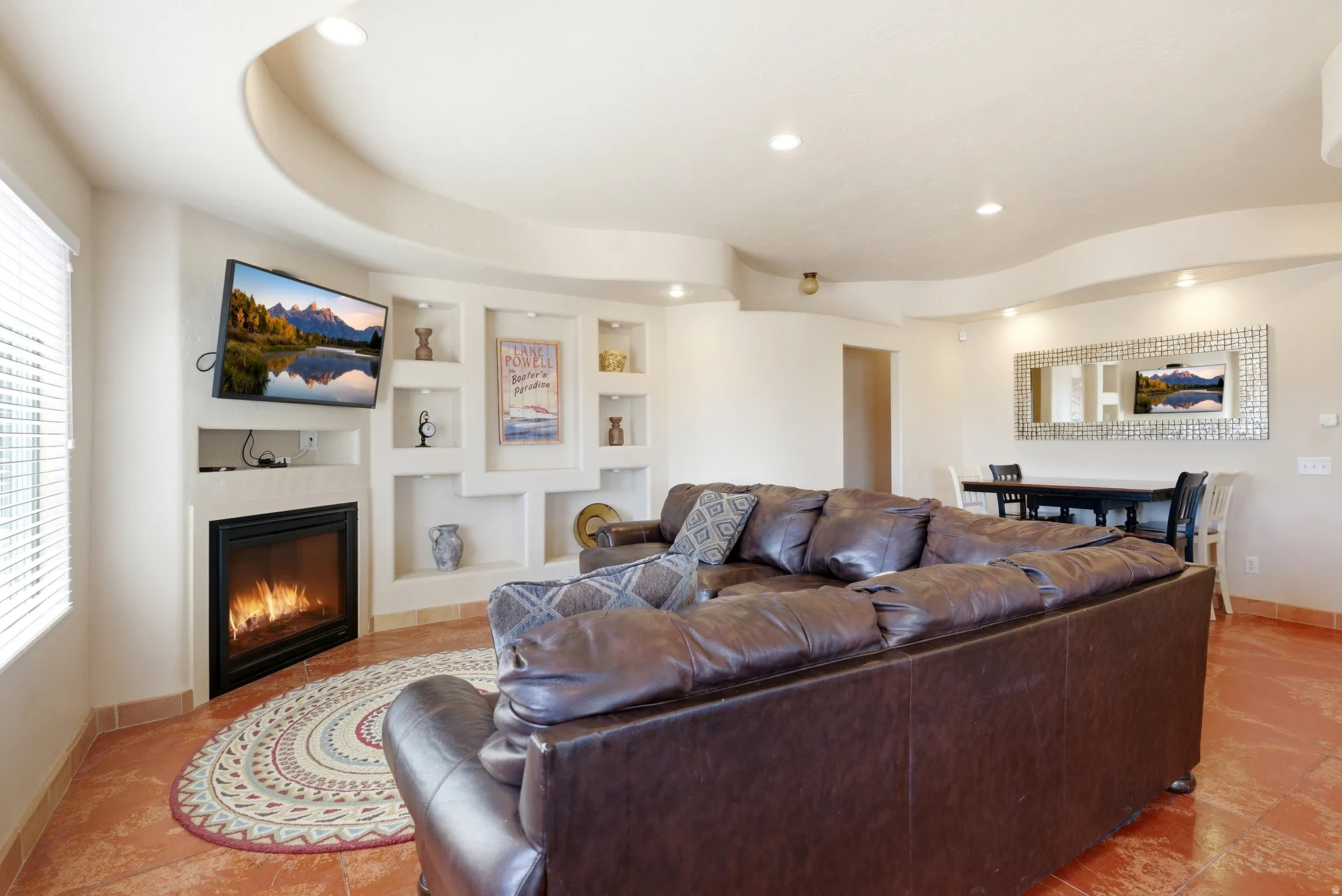 Living area featuring a gas fireplace, built-in shelving, tray ceiling, recessed lighting, and tile flooring