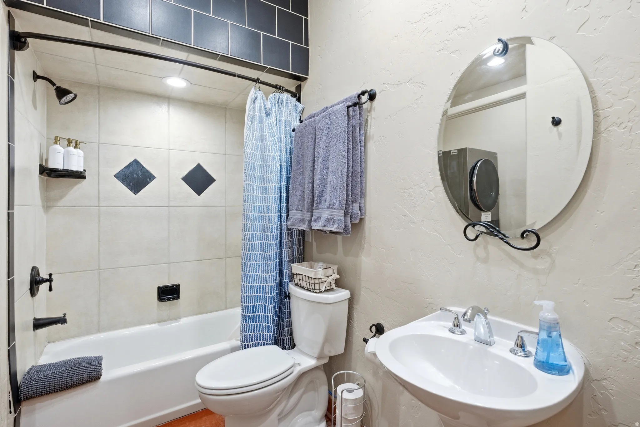 White pedestal sink with chrome faucet, framed by a decorative mirror