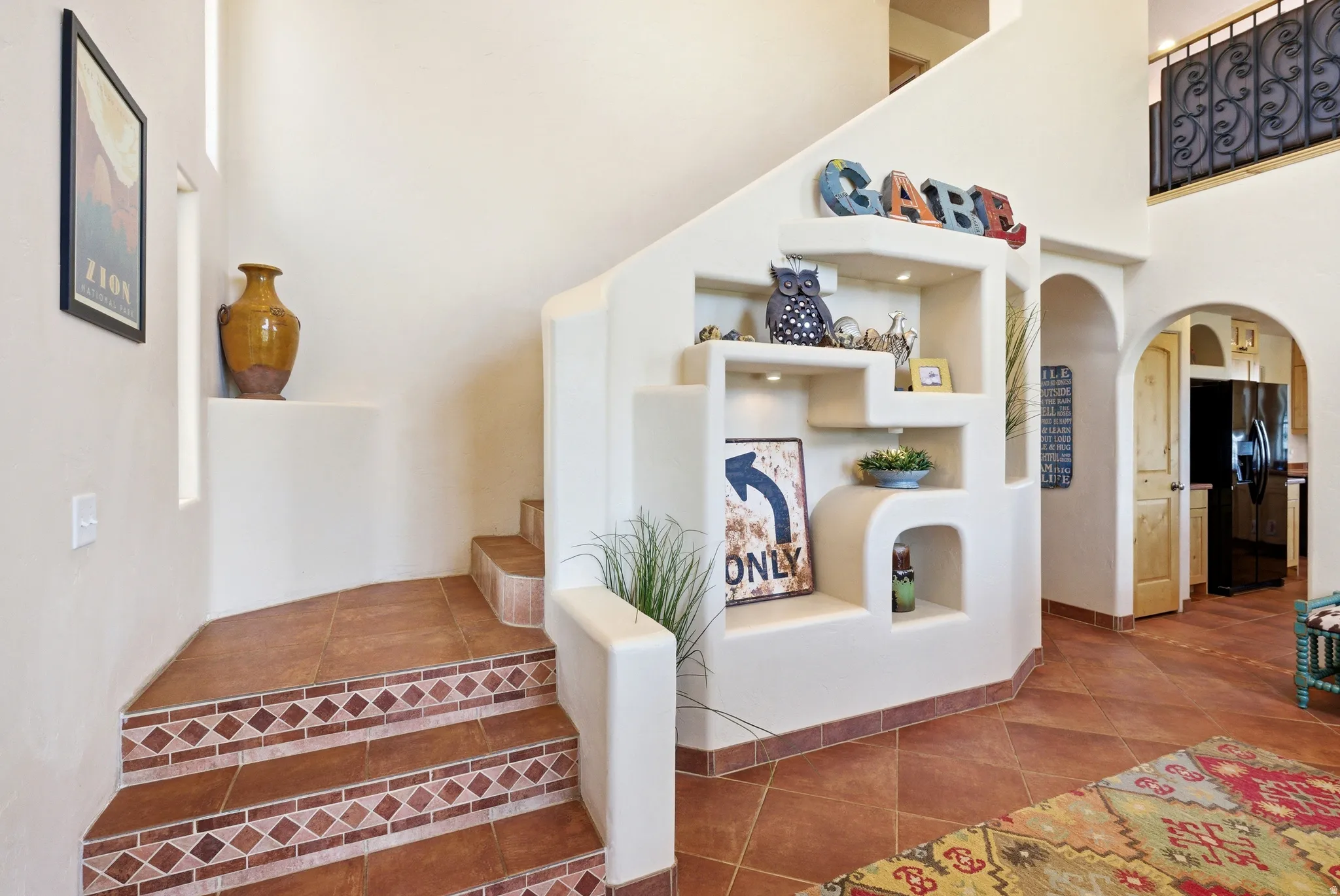 Staircase featuring decorative tile risers and terra cotta flooring