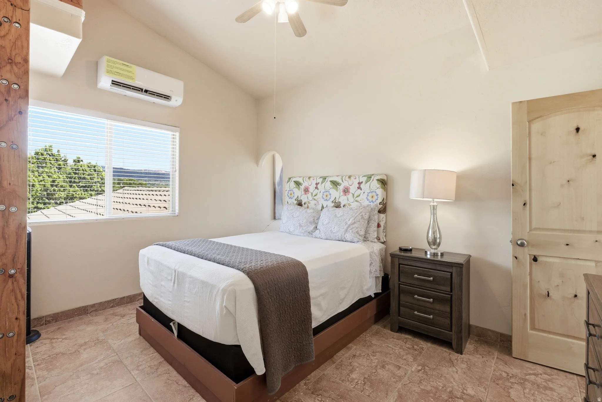 Interior room featuring tile flooring, a window with horizontal blinds, a mini-split AC unit, a ceiling fan, and a solid wood door