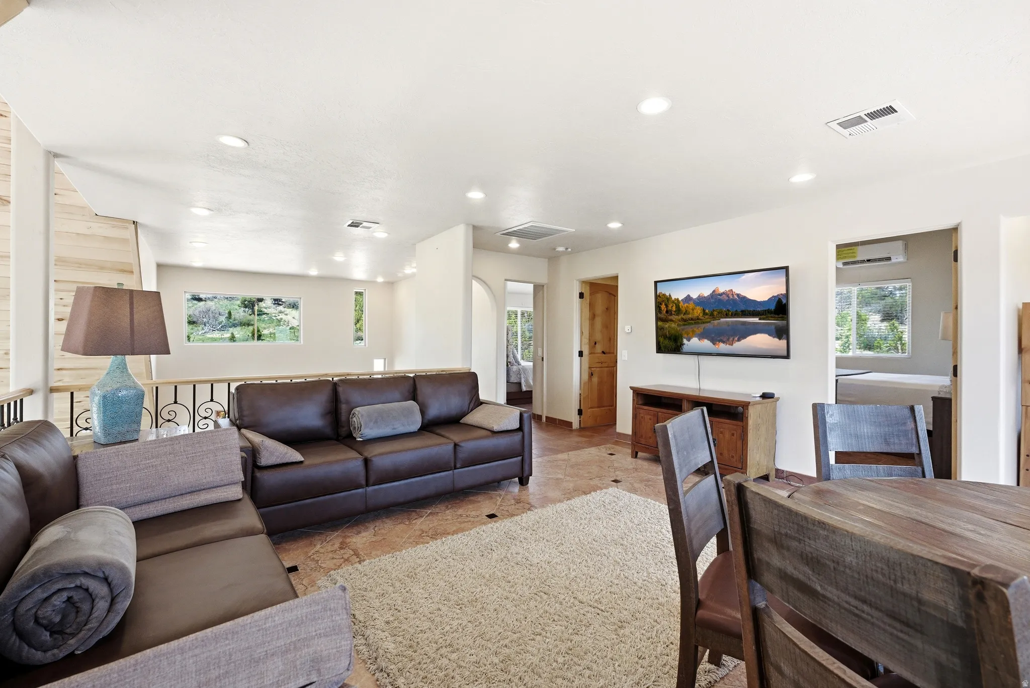 Open-concept living area featuring recessed lighting, a decorative railing, and multiple windows providing natural light
