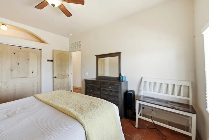 Bedroom featuring wood-finish panel doors, a ceiling fan with integrated lighting, and terra cotta-style flooring