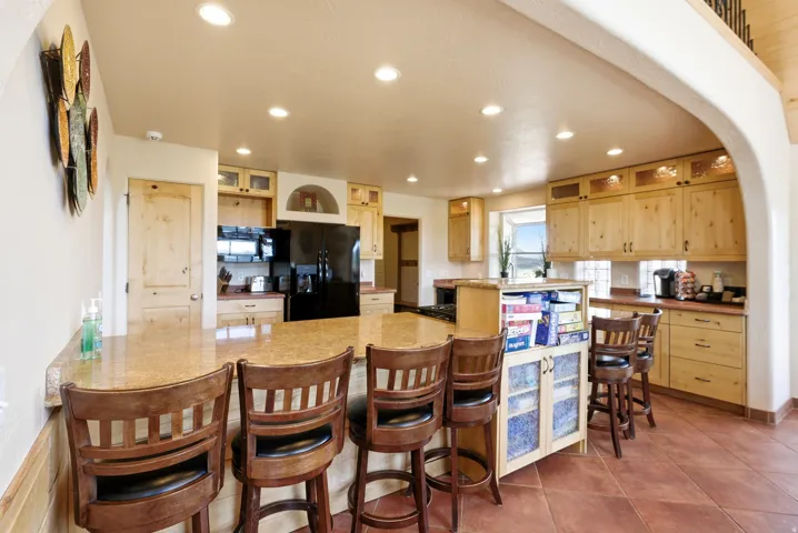 Spacious kitchen featuring an extended island with a breakfast bar, recessed lighting, wood cabinetry, and a full suite of appliances