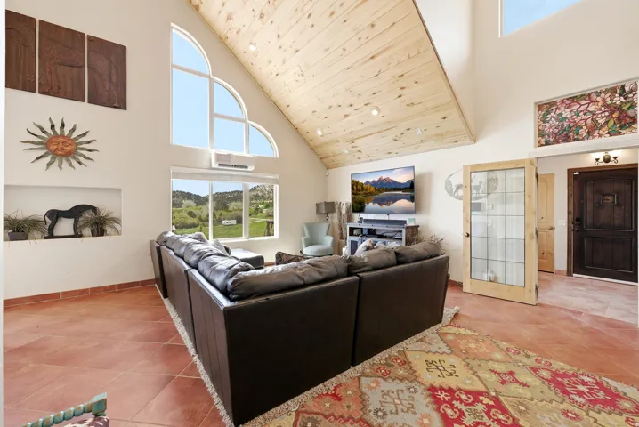 Vaulted wood-paneled ceiling, large arched window, multiple recessed lighting fixtures, built-in wall niche, and tile flooring