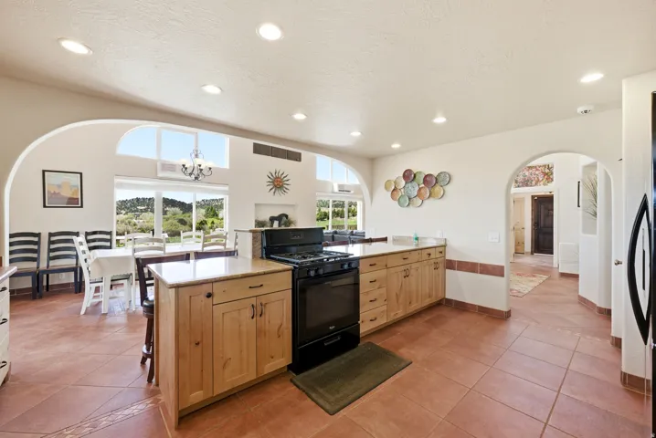 Kitchen featuring extensive wood cabinetry, a black range with an overhead microwave, and a peninsula with a light-toned countertop