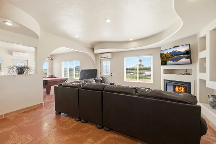 Spacious living area featuring terra cotta-style flooring and a corner fireplace with built-in shelving