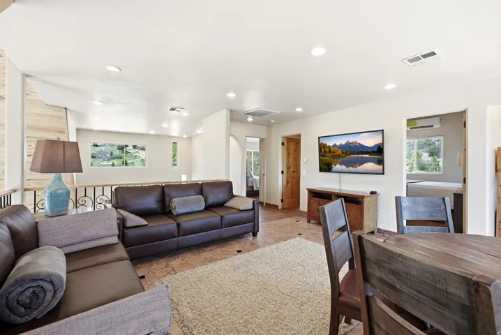 Open-concept living area featuring recessed lighting, a decorative railing, and multiple windows providing natural light