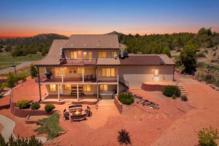 Multi-level exterior featuring balconies, an outdoor patio with a fire pit, a hot tub, and terraced landscaping