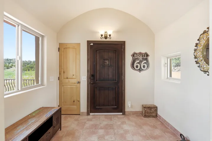 Arched entryway featuring a dark wood-finish entry door, light wood-finish interior door, tiled flooring, and a large window