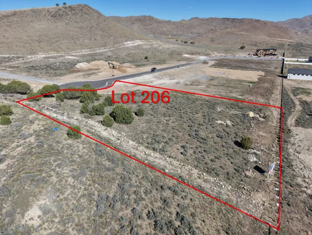 Expansive land parcel featuring natural desert flora, a paved road, and distant mountain backdrops