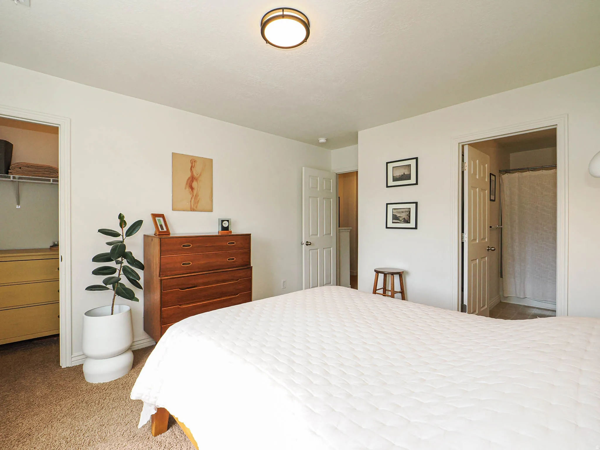Neutral interior room featuring two white paneled doors, one leading to a closet with built-in shelving and another to a bathroom