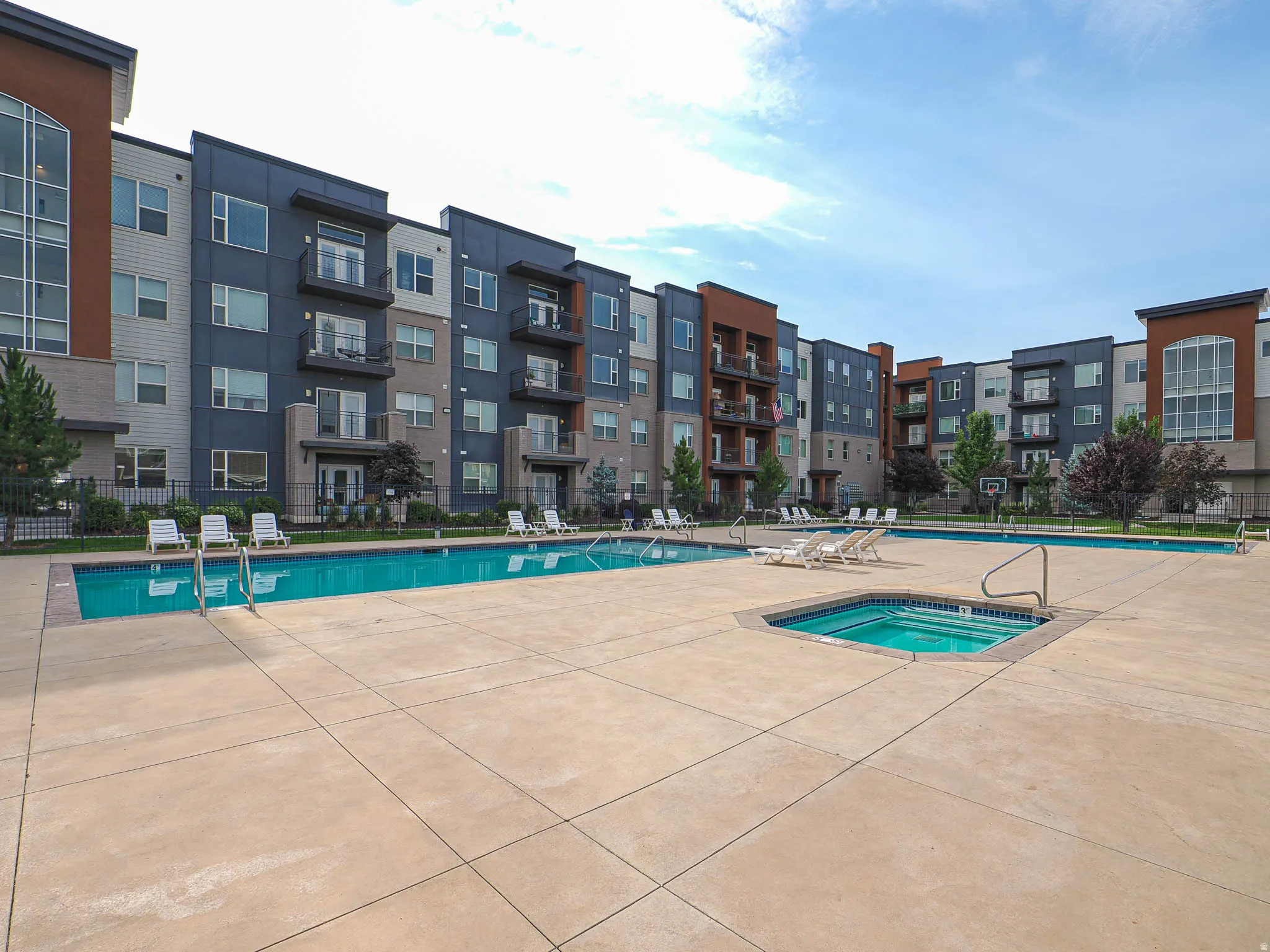 Outdoor swimming pool area featuring a large rectangular pool and a separate square spa