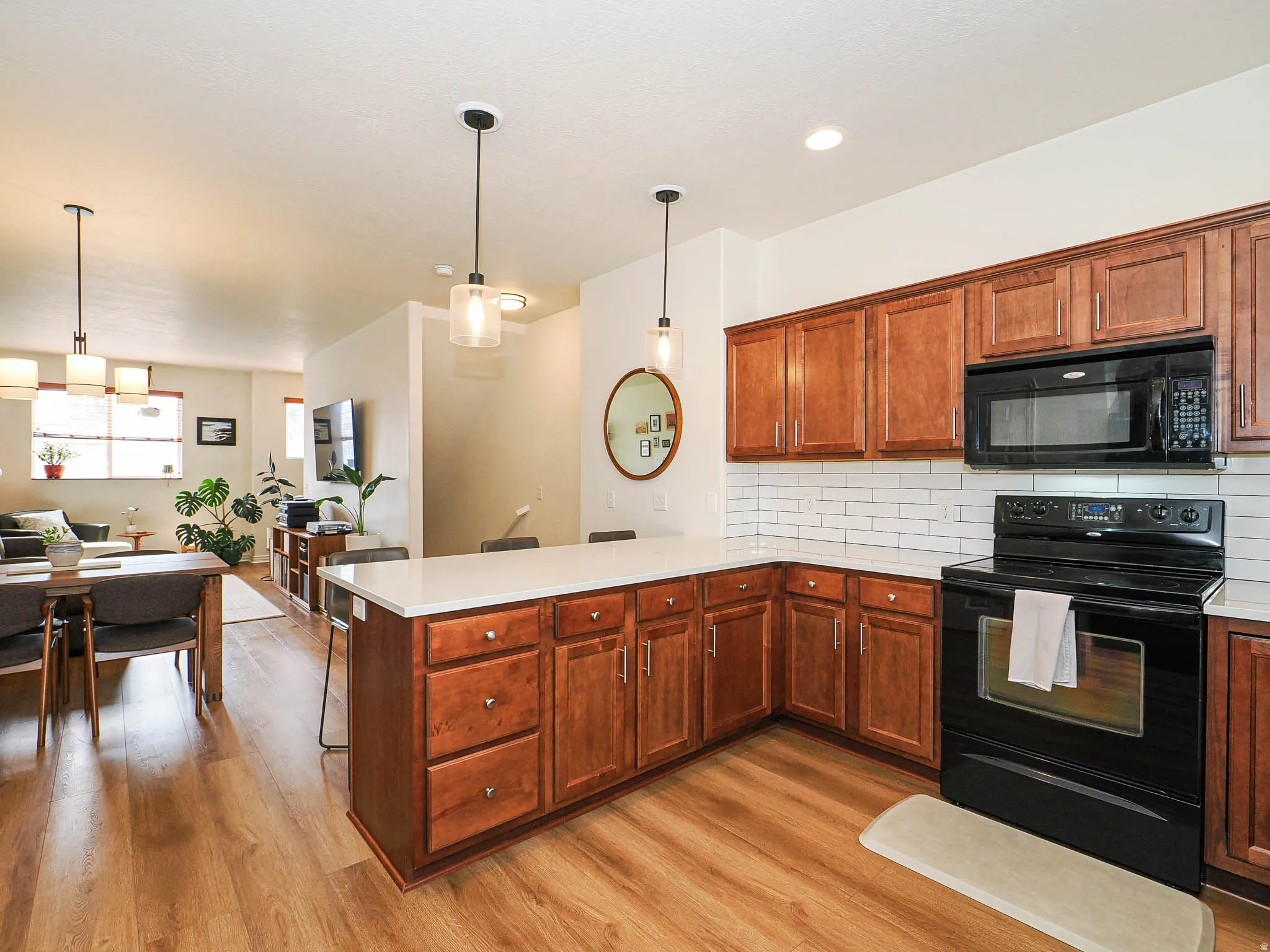 Kitchen featuring wood-finish cabinetry, white countertops, subway tile backsplash, and black appliances