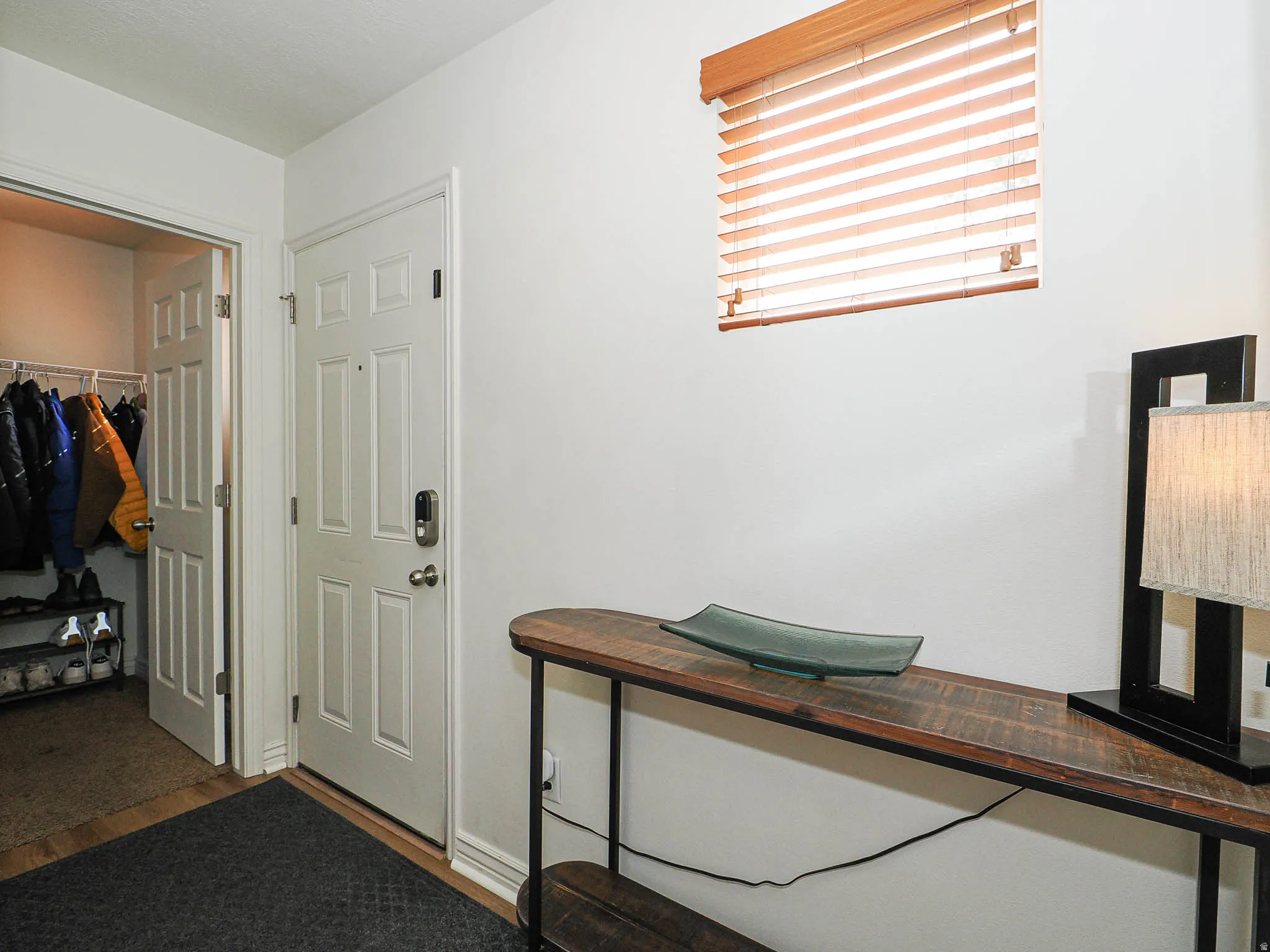 Entryway featuring a panel door, built-in closet with bifold doors, and wood-finish flooring