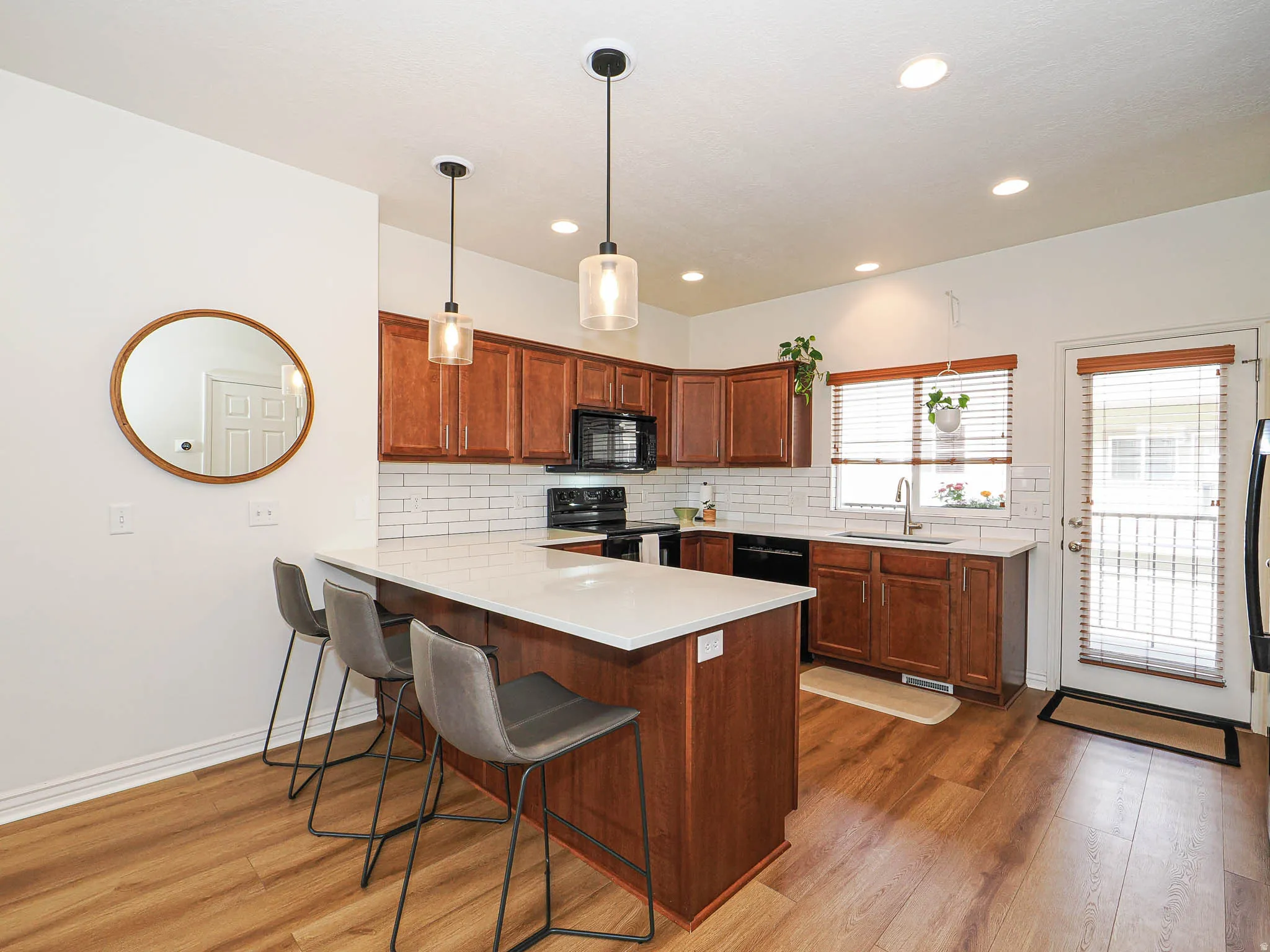 Well-appointed kitchen featuring wood-finish flooring, white subway tile backsplash, recessed lighting, and pendant lighting fixtures