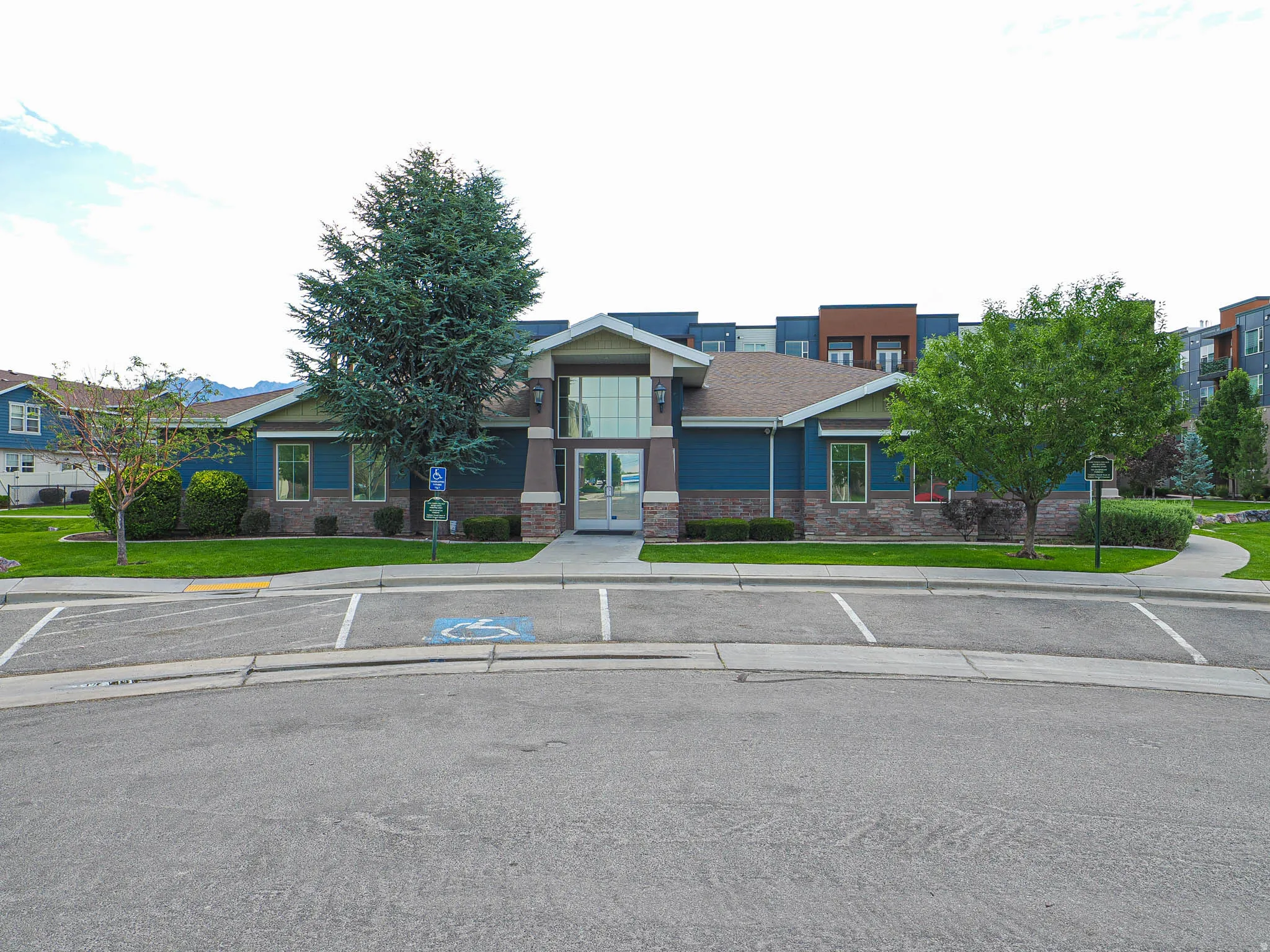 Contemporary building featuring a prominent glass entrance, blue siding, and stone accents