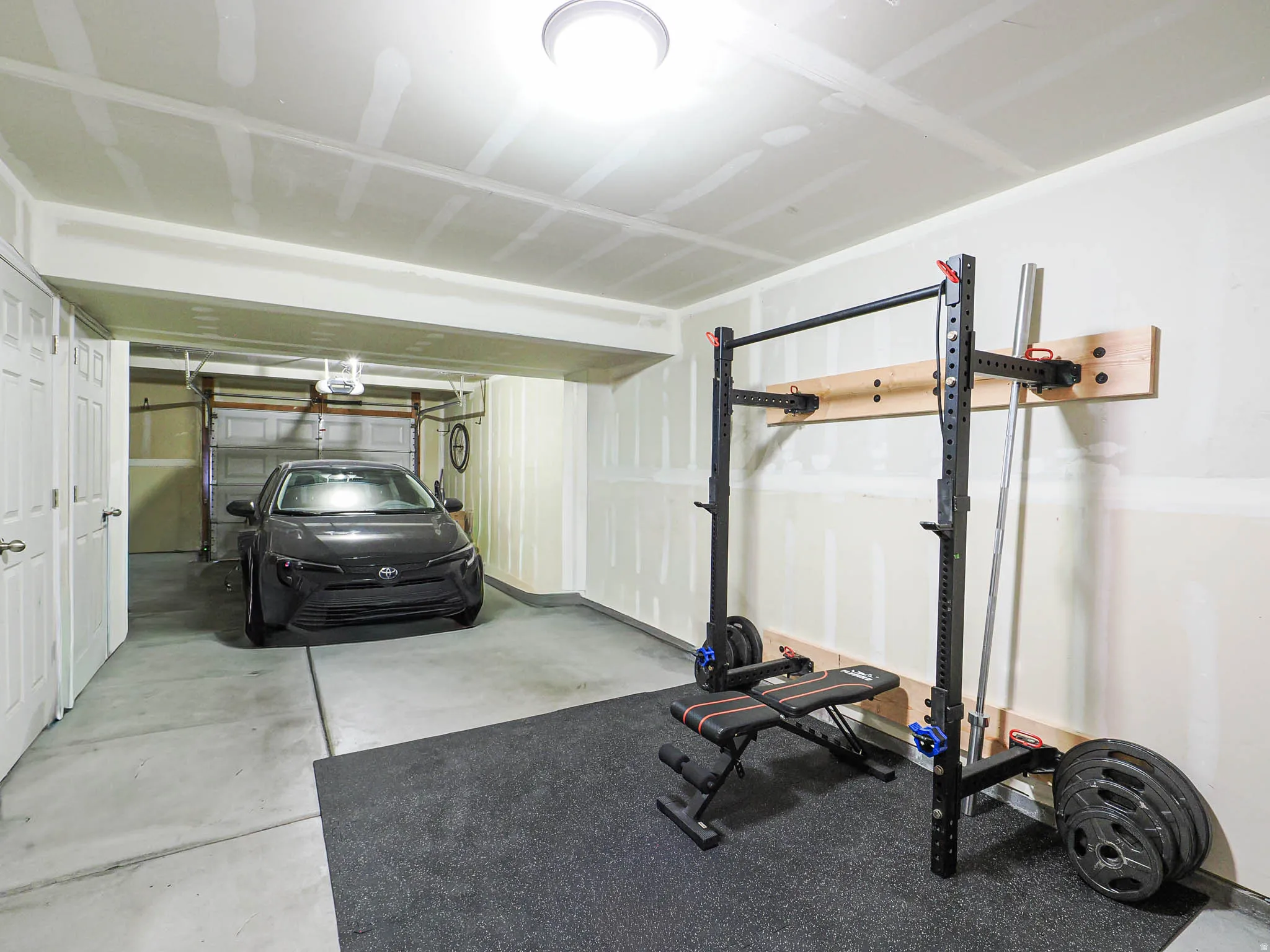 Attached two-car garage with concrete flooring, overhead lighting, and interior access doors
