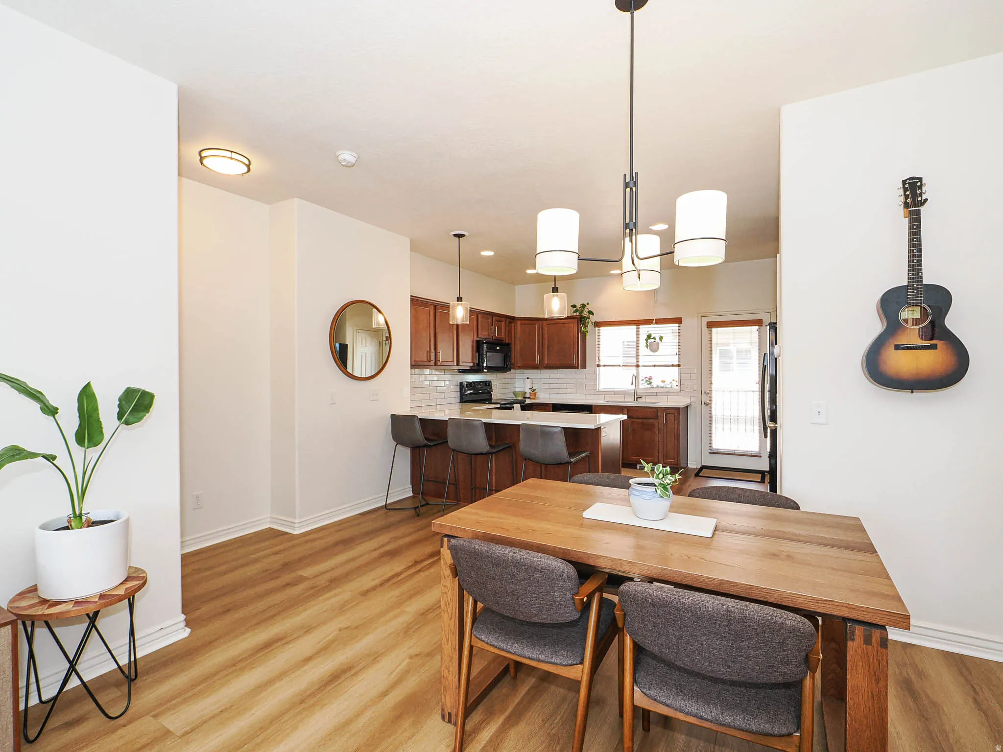 Open-concept living space featuring wood-finish flooring, a modern chandelier, white walls, and bright recessed lighting