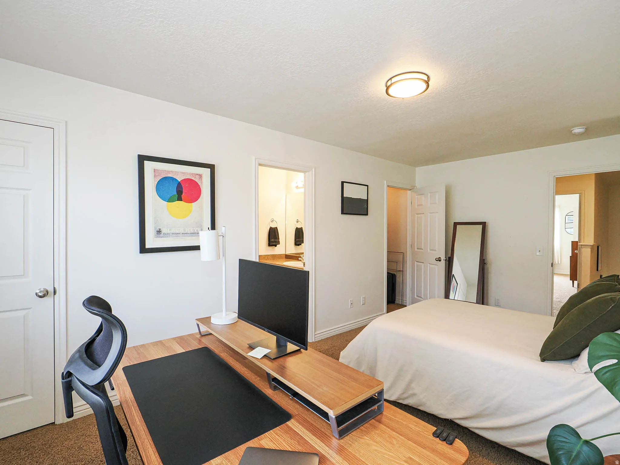 Carpeted room featuring a ceiling-mounted light fixture, white interior doors, and a partial view into an adjacent bathroom with a vanity