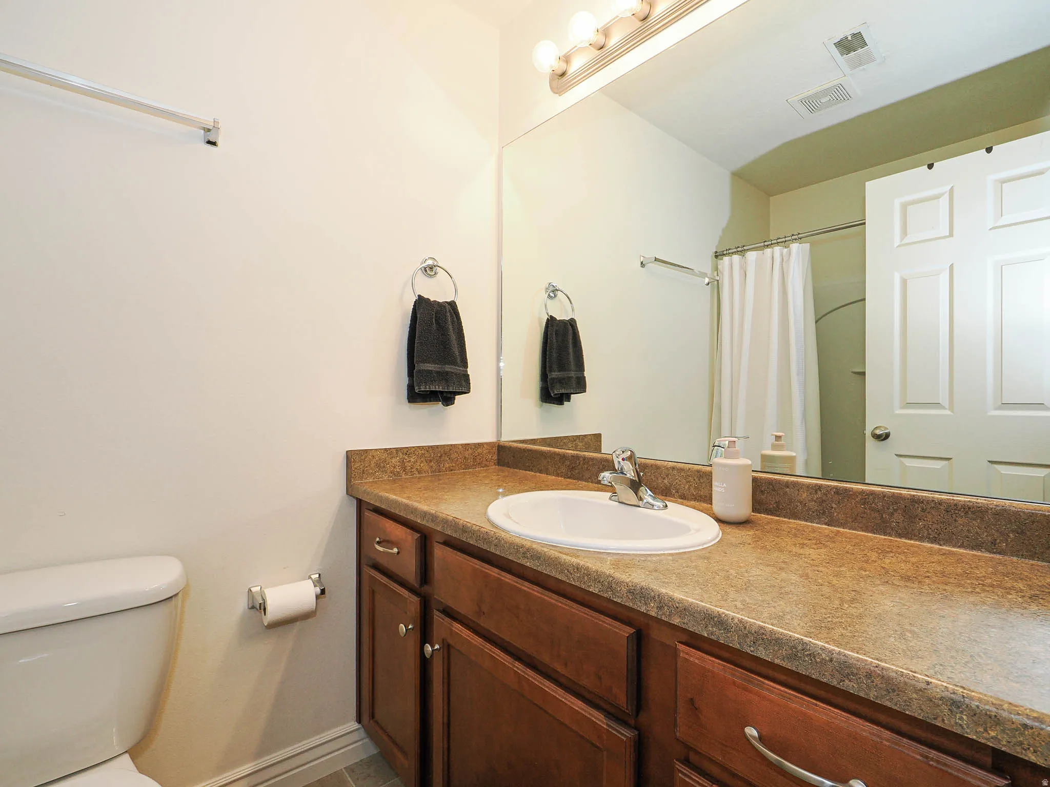 Bathroom vanity featuring a light-colored countertop with an integrated sink and chrome faucet