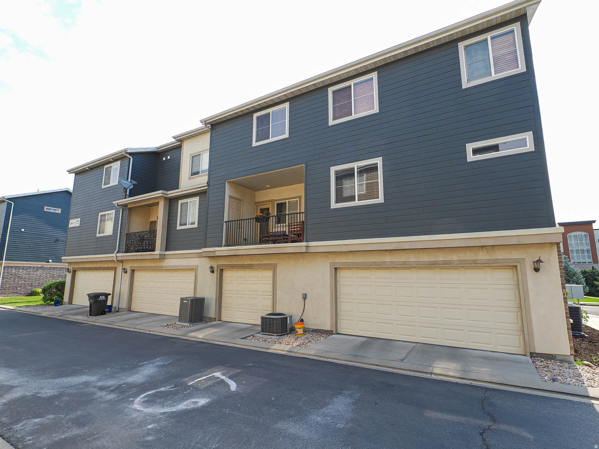 Contemporary multi-level exterior featuring dark blue horizontal siding and light-colored stucco