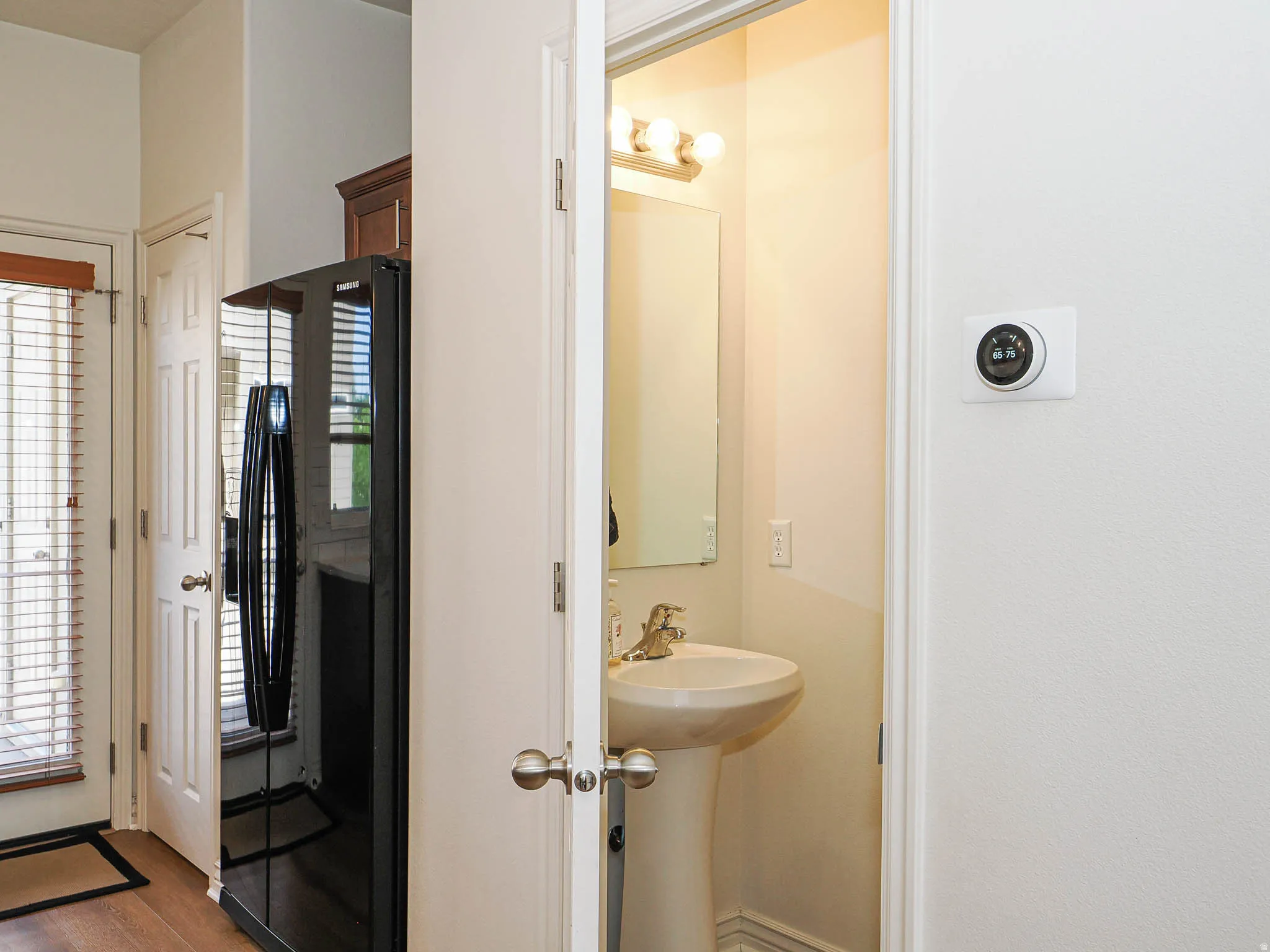 Pedestal sink with brass-finish faucet, mirror, and vanity lighting fixture