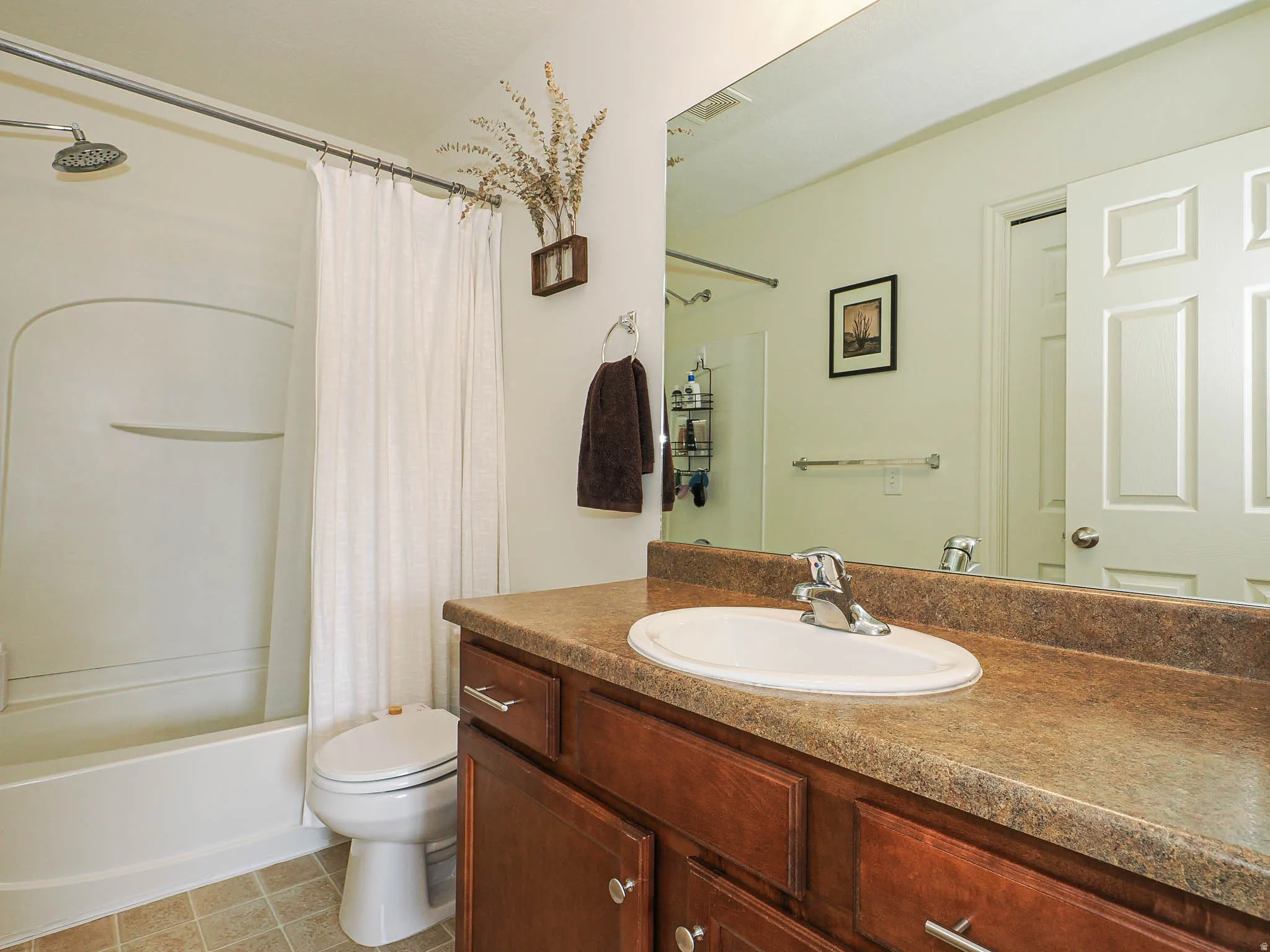 Bathroom featuring a shower-tub combination, a vanity with a laminate countertop, and an oval sink with a chrome faucet