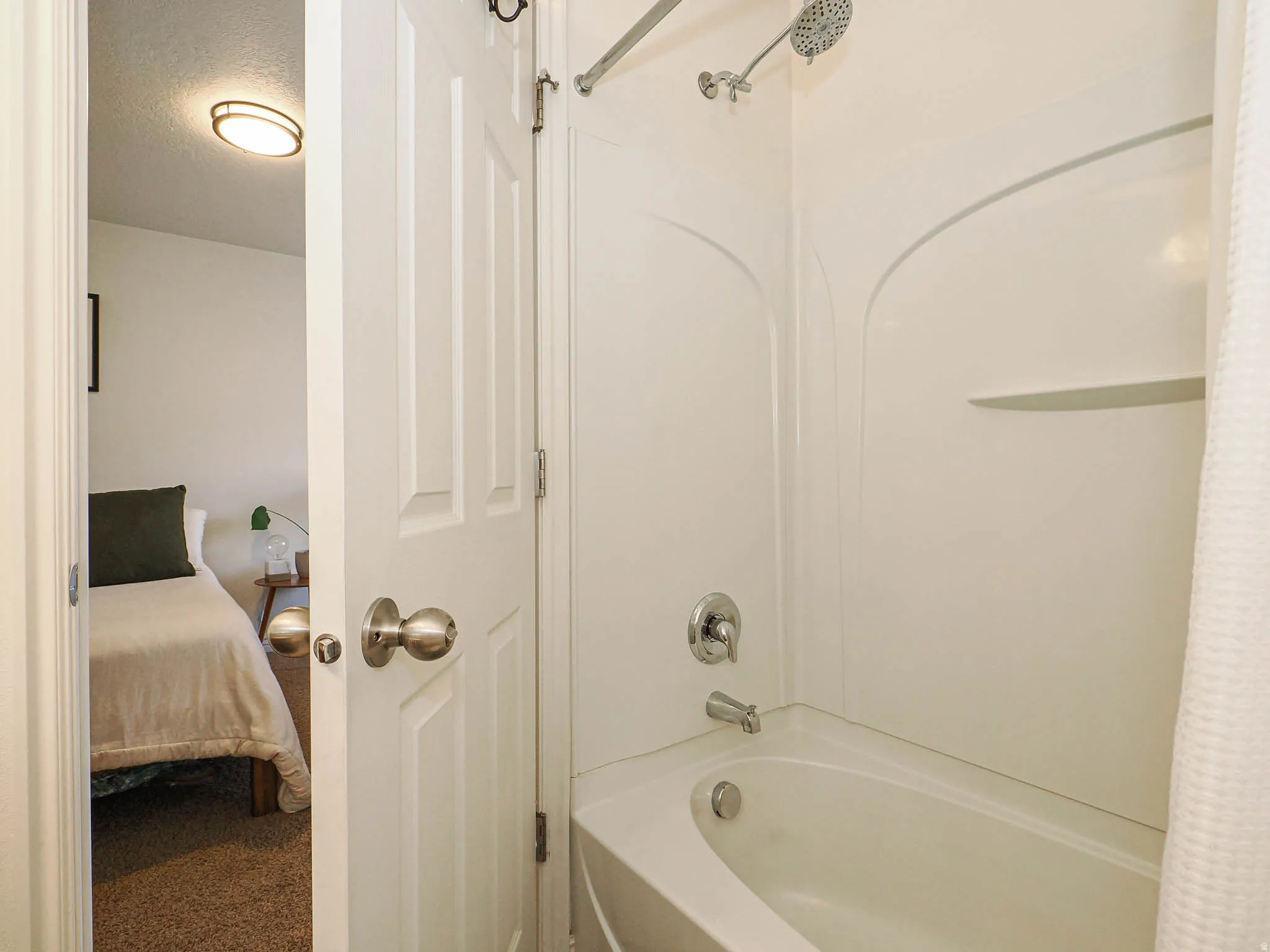 Fiberglass tub and shower combination with chrome fixtures and integrated shelving