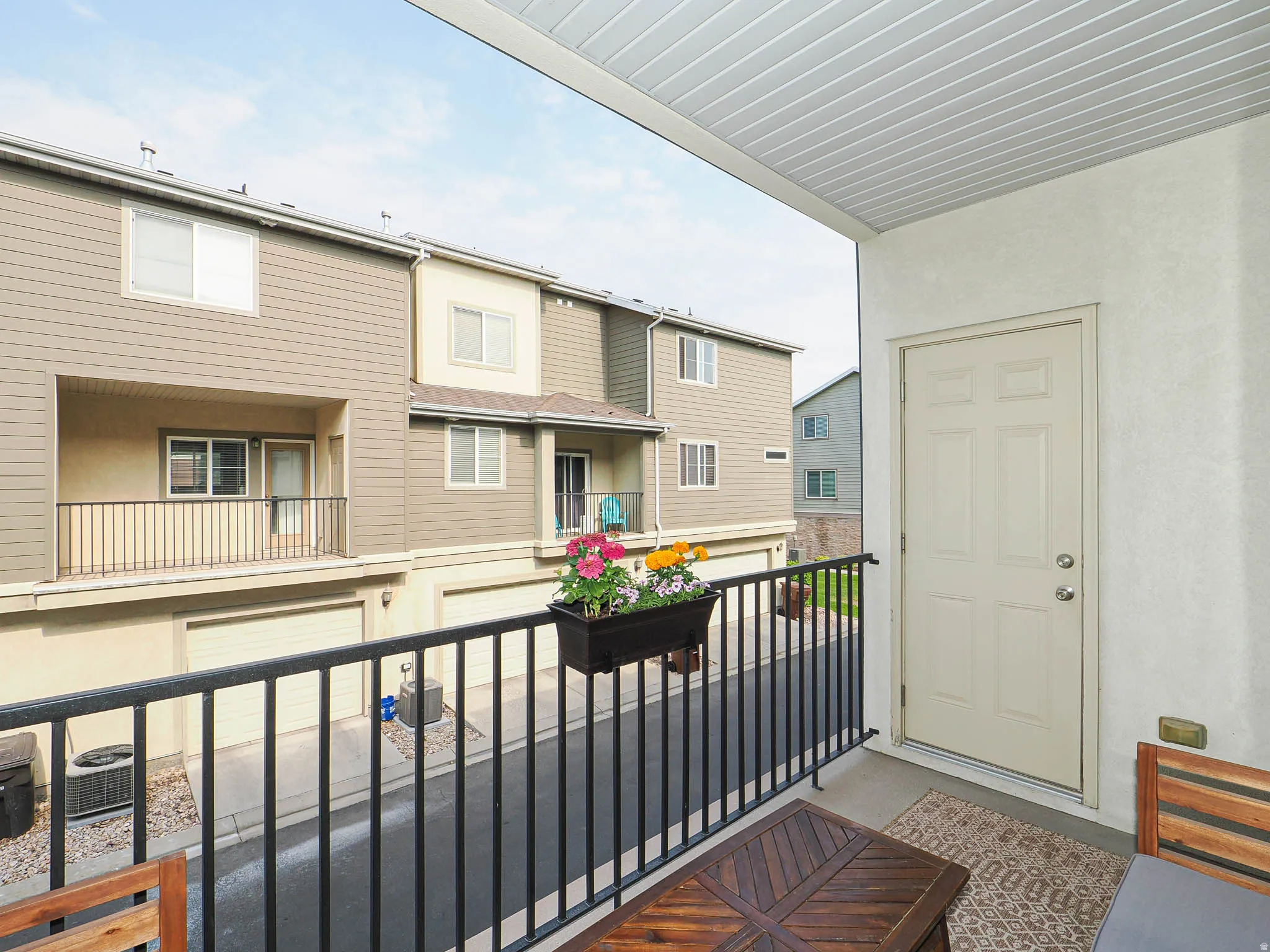 Private balcony featuring a black metal railing, concrete flooring, and a paneled entry door
