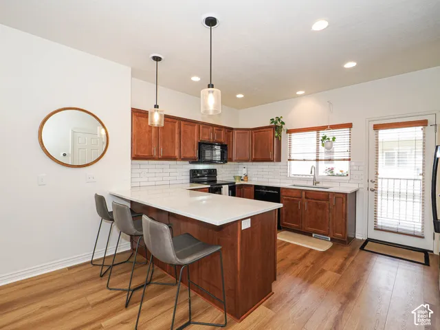 Well-appointed kitchen featuring wood-finish flooring, white subway tile backsplash, recessed lighting, and pendant lighting fixtures