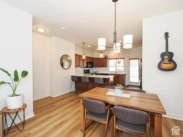 Open-concept living space featuring wood-finish flooring, a modern chandelier, white walls, and bright recessed lighting