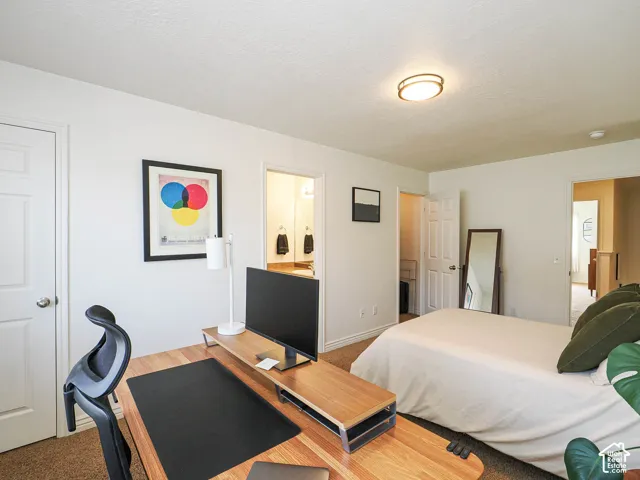 Carpeted room featuring a ceiling-mounted light fixture, white interior doors, and a partial view into an adjacent bathroom with a vanity