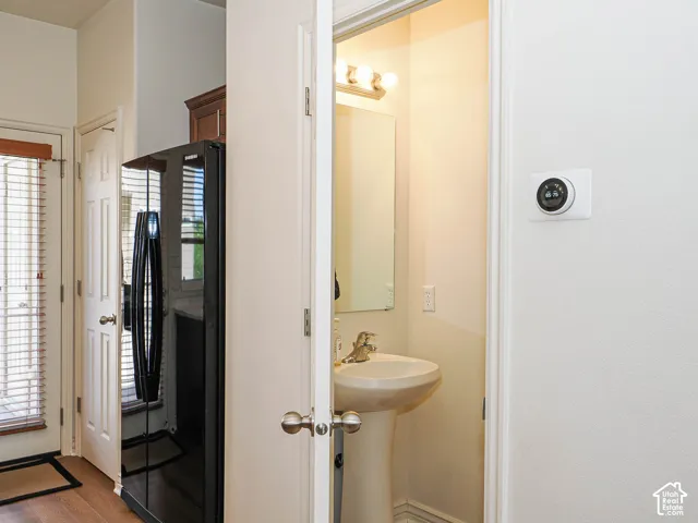 Pedestal sink with brass-finish faucet, mirror, and vanity lighting fixture