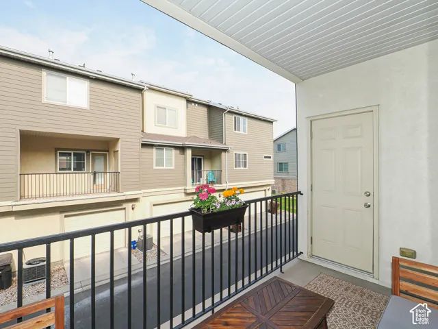 Private balcony featuring a black metal railing, concrete flooring, and a paneled entry door