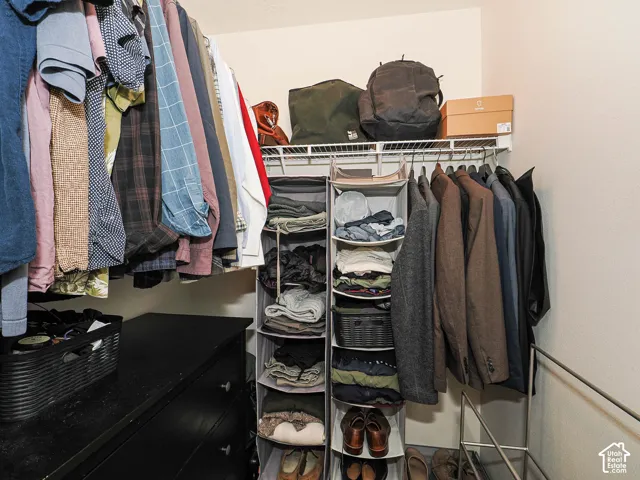 Wardrobe space featuring white wire shelving, a black dresser, and neutral wall tones