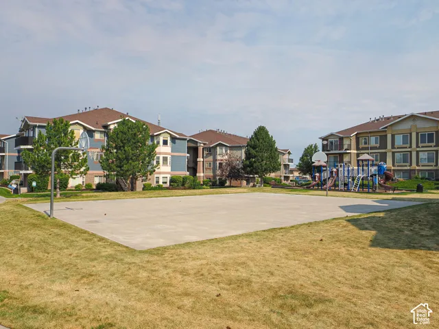 Expansive concrete court with basketball hoop, bordered by green space