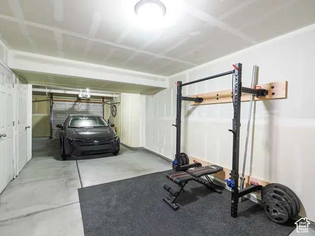 Attached two-car garage with concrete flooring, overhead lighting, and interior access doors