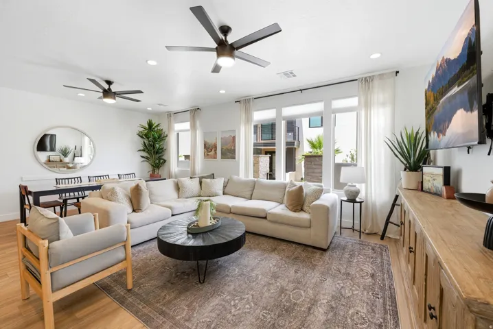 Open-concept living area featuring light wood-finish flooring, recessed lighting, and dual ceiling fans