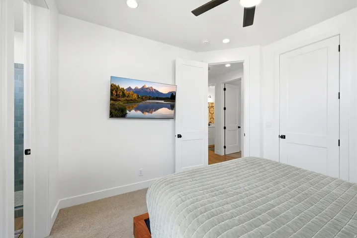 Carpeted room with a wall-mounted television, recessed lighting, and a ceiling fan