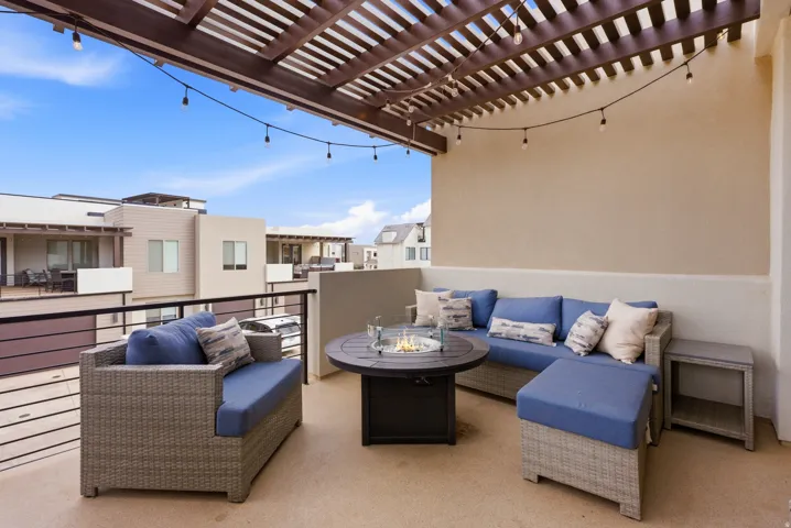 Expansive rooftop patio featuring a wood pergola and string lighting