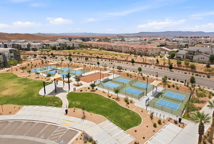 Community park featuring multiple pickleball courts, grassy recreation areas, and shaded gathering spaces