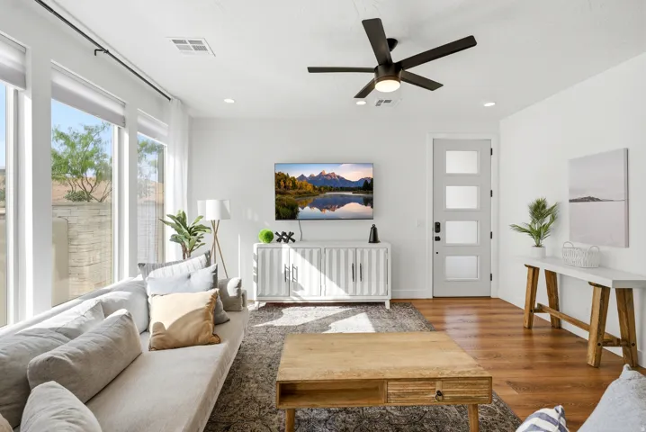 Spacious living area featuring large windows, wood-finish flooring, recessed lighting, and a modern ceiling fan