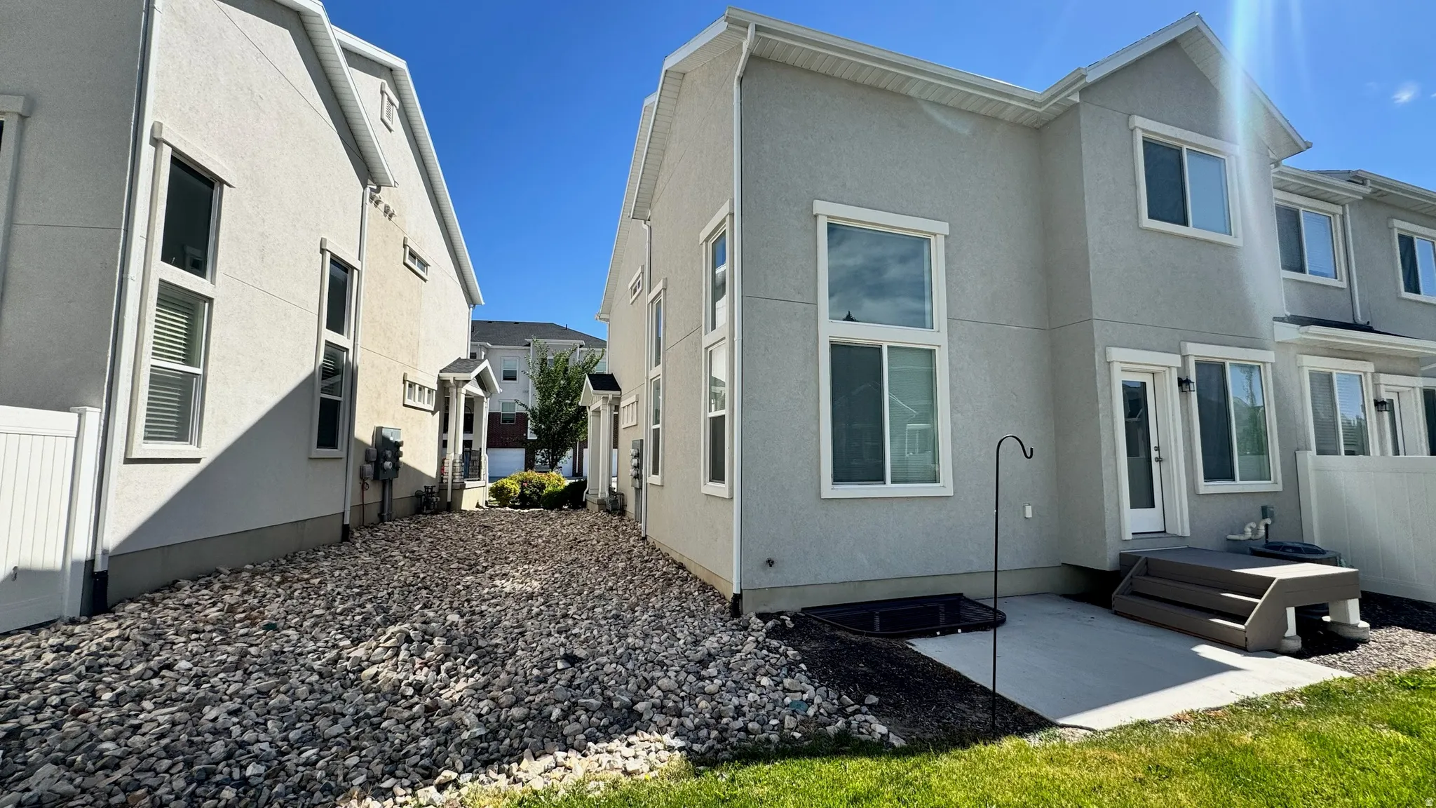 Rear exterior featuring stucco siding, multiple windows, and a concrete patio