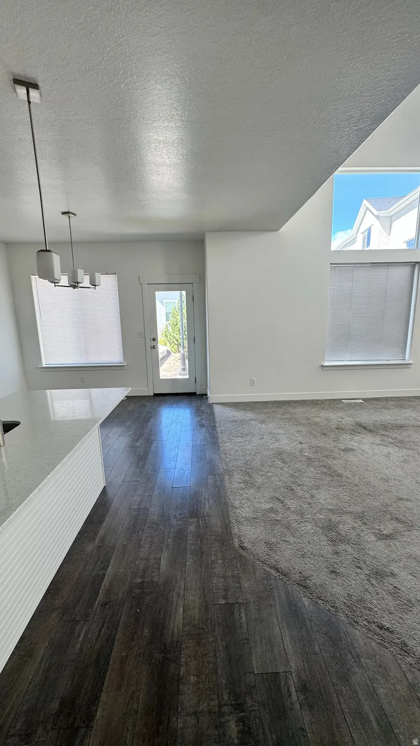 Open-concept living space featuring wood-finish flooring, a two-story ceiling, and a contemporary chandelier