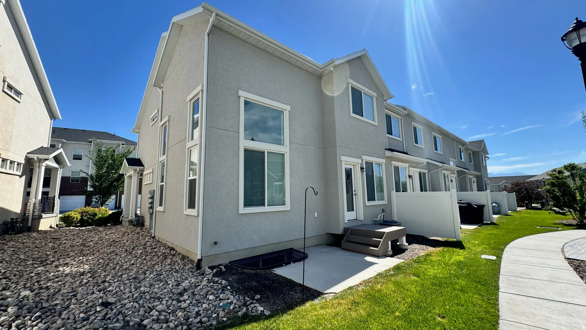 Rear exterior featuring a concrete patio, grassy yard, and white privacy fencing
