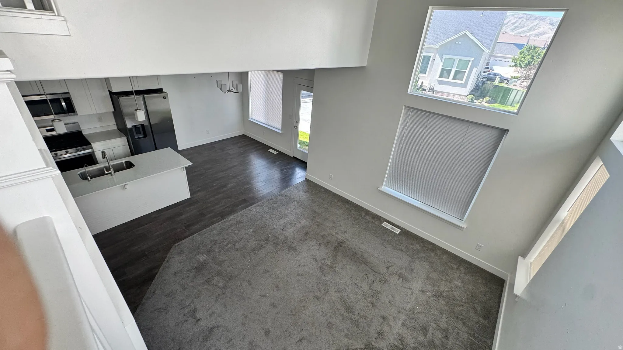 Open-concept living space featuring a high vaulted ceiling, large windows with mountain scenery, and a modern kitchen